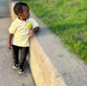 A young boy standing on the side of a road.