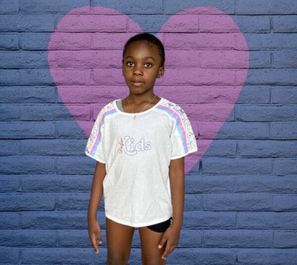 A young boy standing in front of a brick wall.