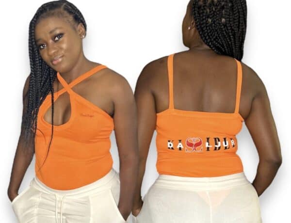 A woman wearing an orange tank top with the words " # baddie " on it.