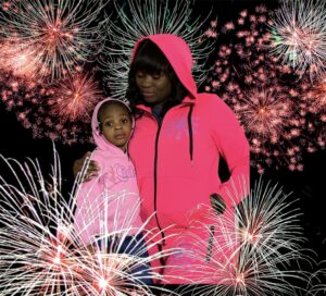 A woman and child in front of fireworks.