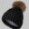 A black hat with a brown pom-pom on top of it.