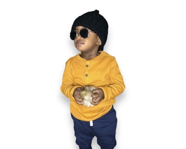 A child wearing sunglasses and a hat holding something.